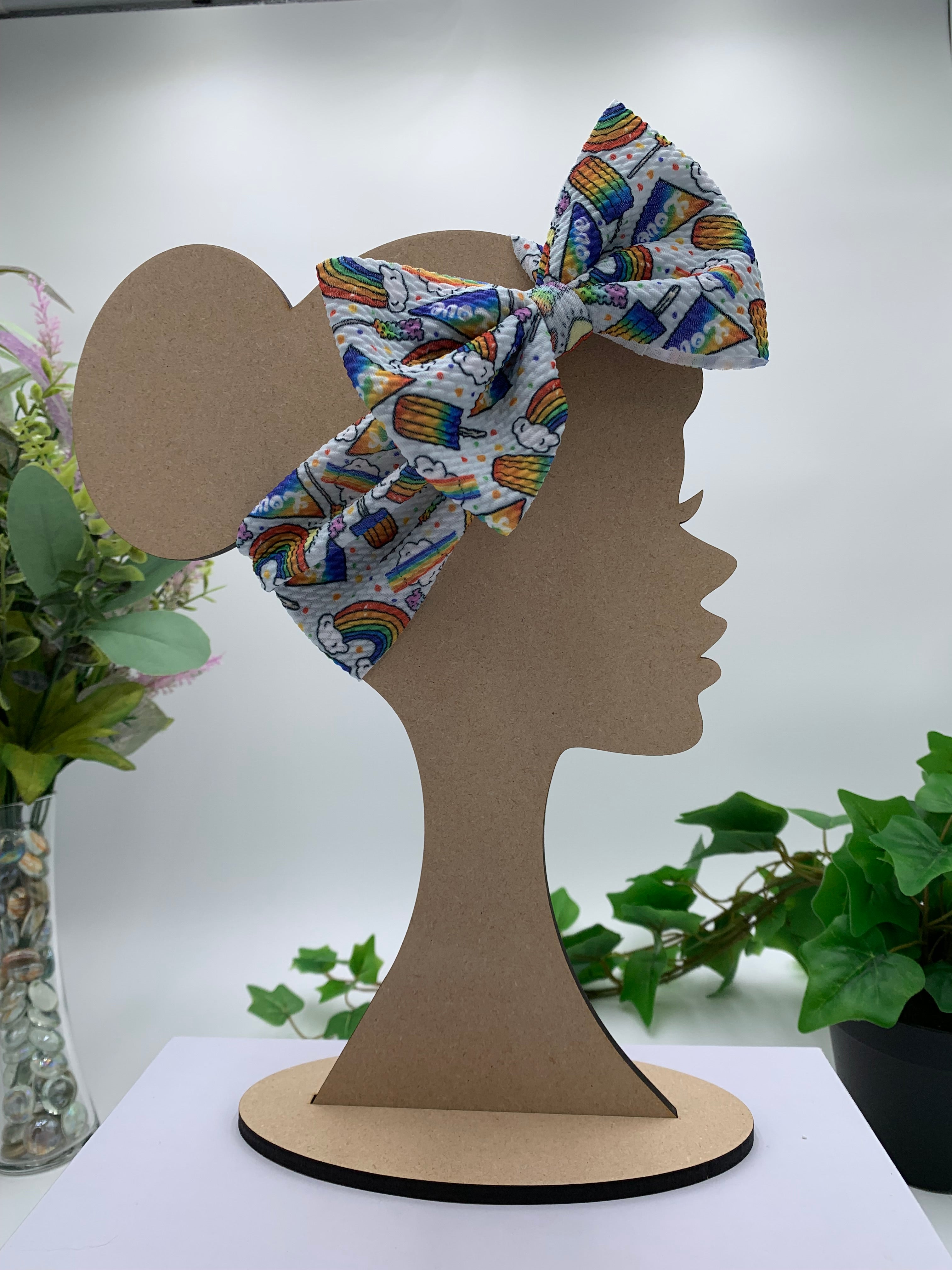 Colorful rainbow popsicles big bow headband on a mannequin head with a white background and greenery 