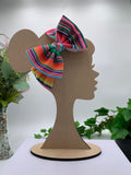 Colorful Serape themed big bow headband on a mannequin head with a white background and greenery 