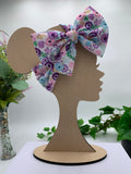 Spring flowers themed big bow headband on a mannequin head with a white background and greenery 