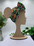 Colorful tie dye headband on a mannequin head with a white background and greenery 