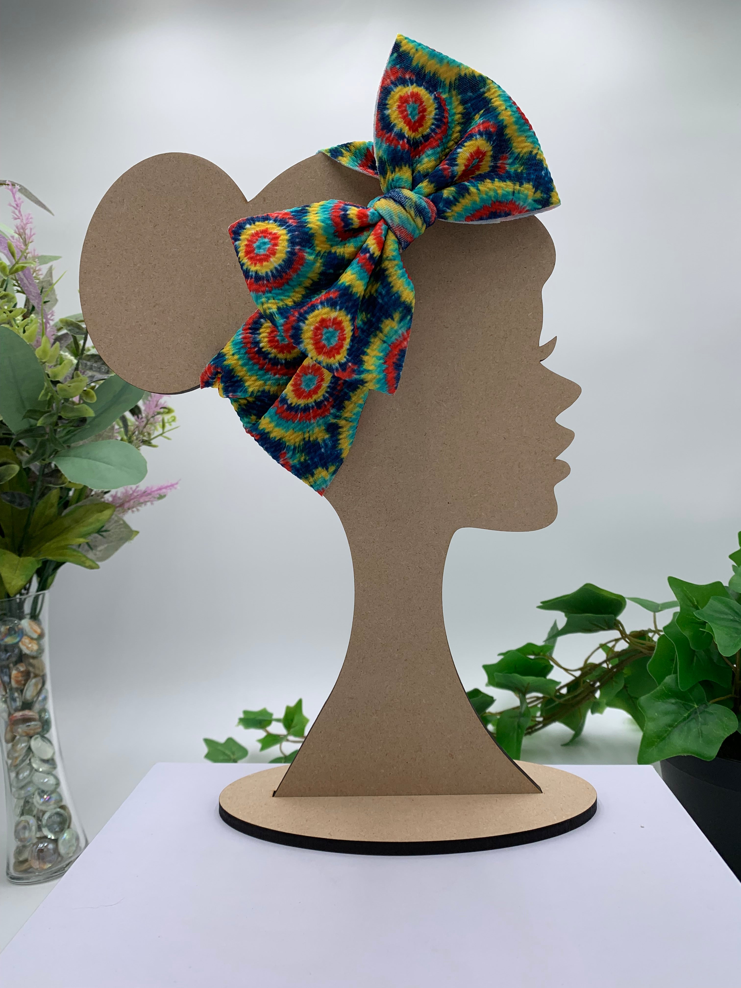Colorful tie dye headband on a mannequin head with a white background and greenery 