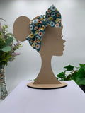 Colorful floral big bow headband on a mannequin head with a white background and greenery 