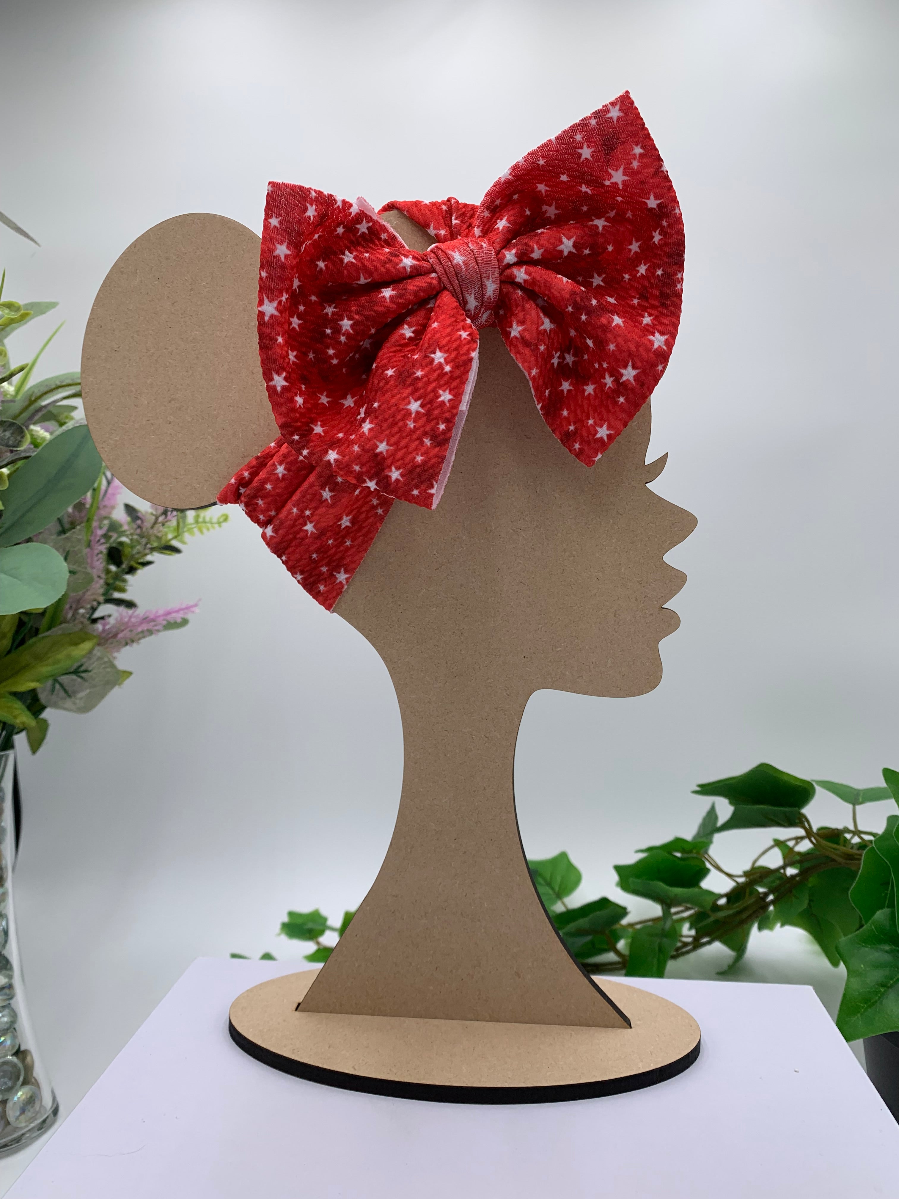 Red 4th of July Stars themed big bow headband on a mannequin head with a white background and greenery 