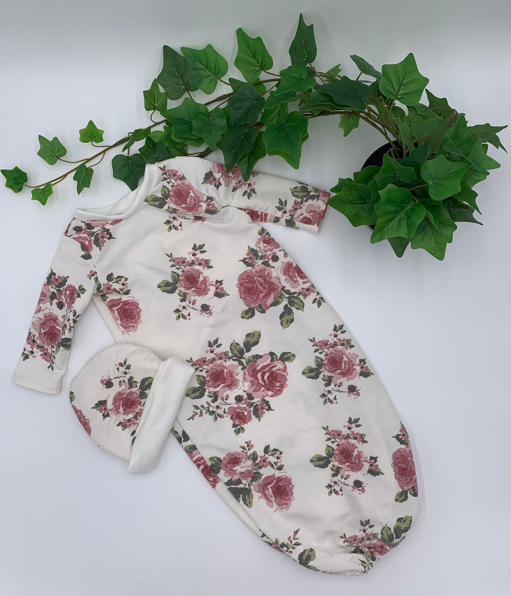 Floral baby sleeper sack with matching beanie on a white background with green leaves.