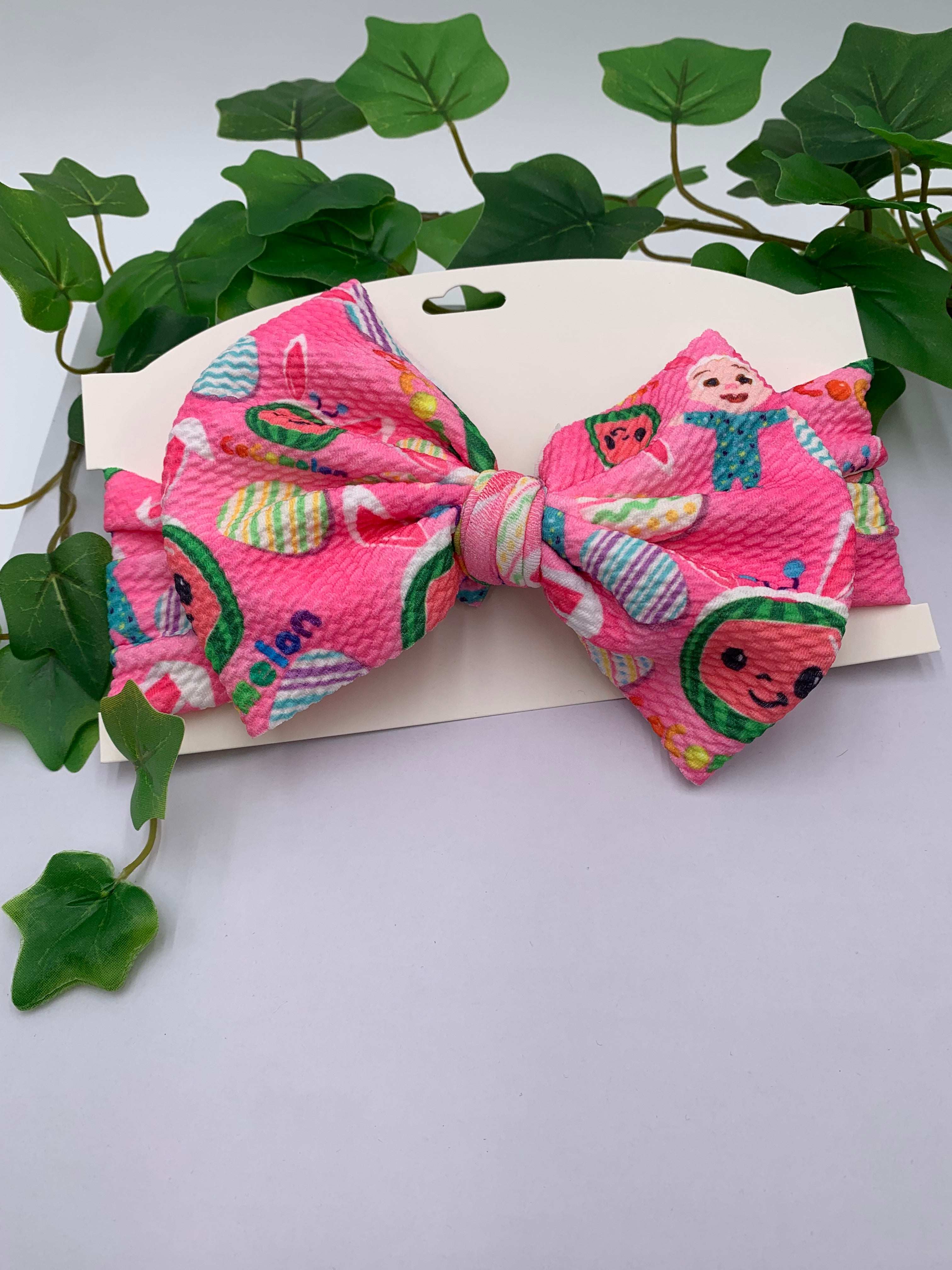 Hot Pink Easter themed big bow headband on a white card with a white background and greenery 