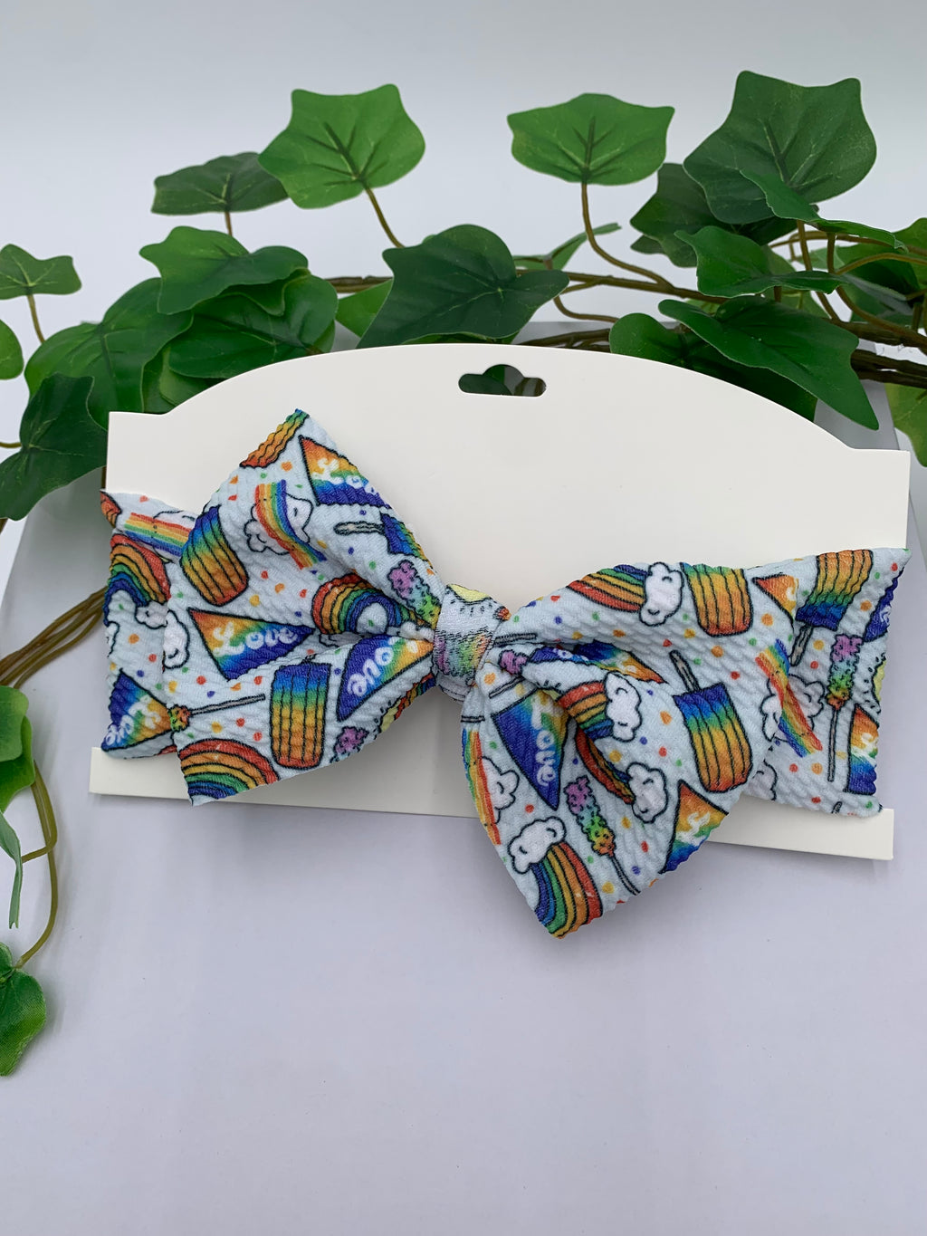 Colorful rainbow popsicles big bow on a white card with a white background and greenery 
