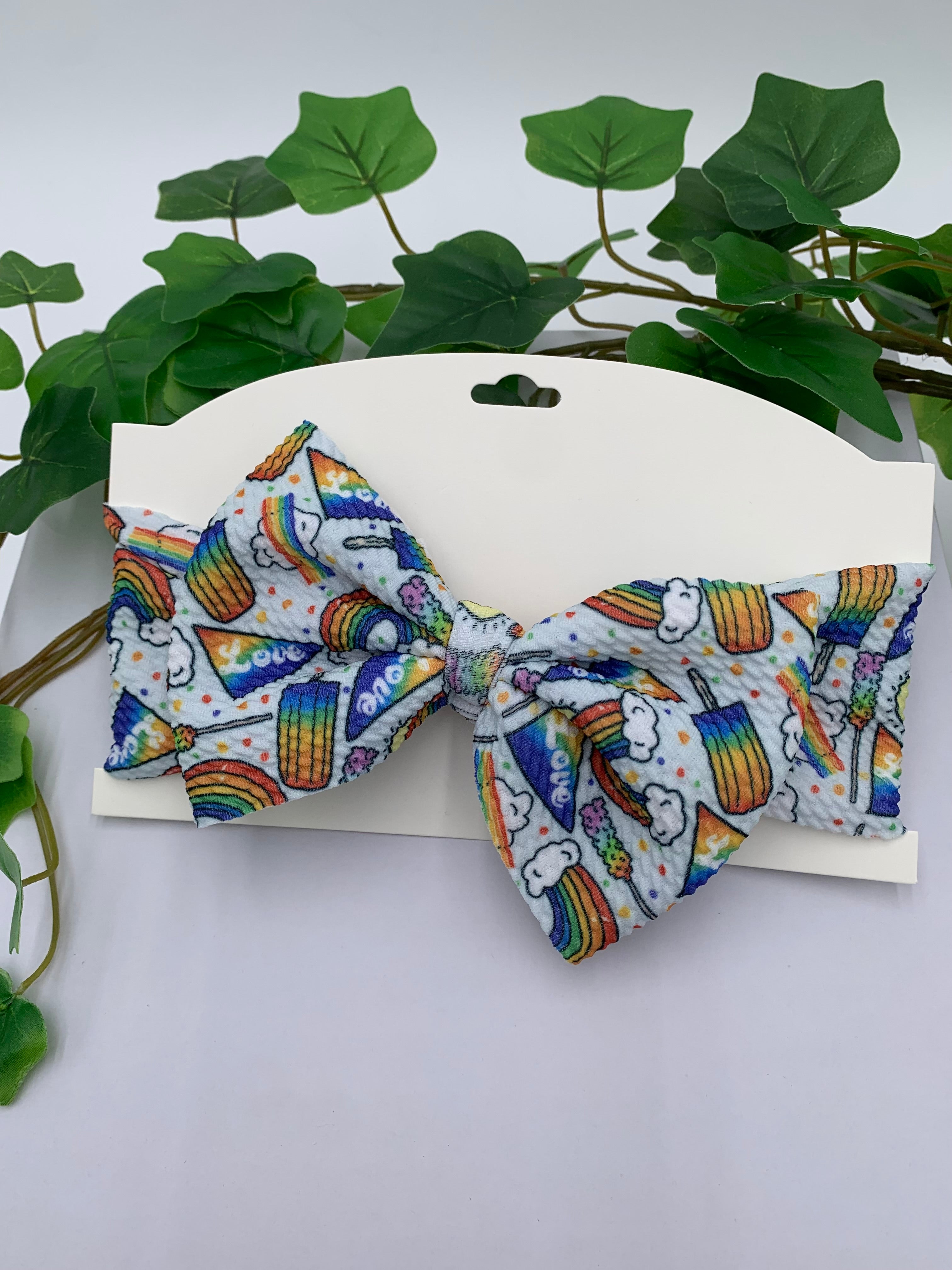 Colorful rainbow popsicles big bow on a white card with a white background and greenery 
