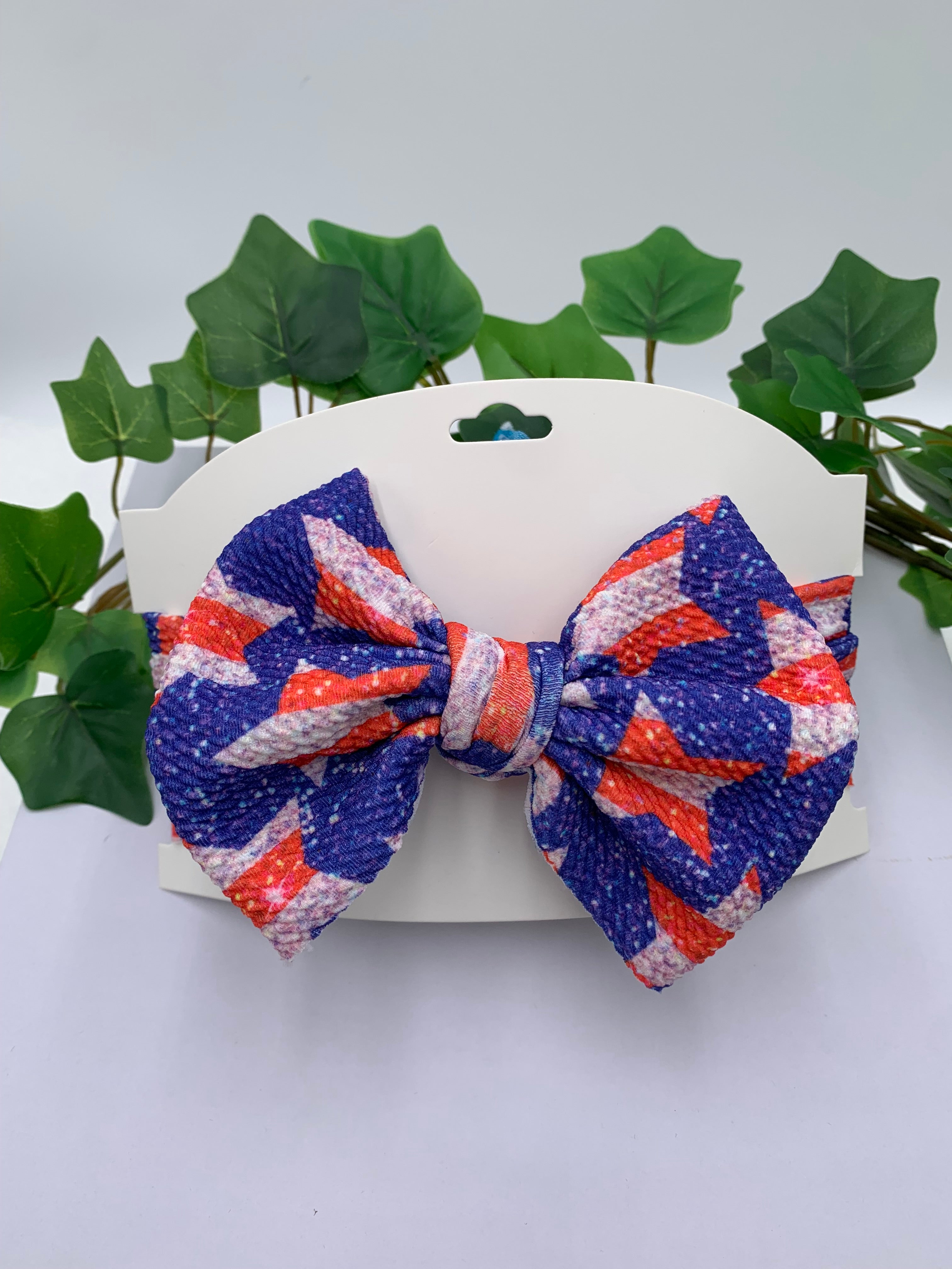 4th of July Star themed big bow headband on a white card stock with a white background and greenery 