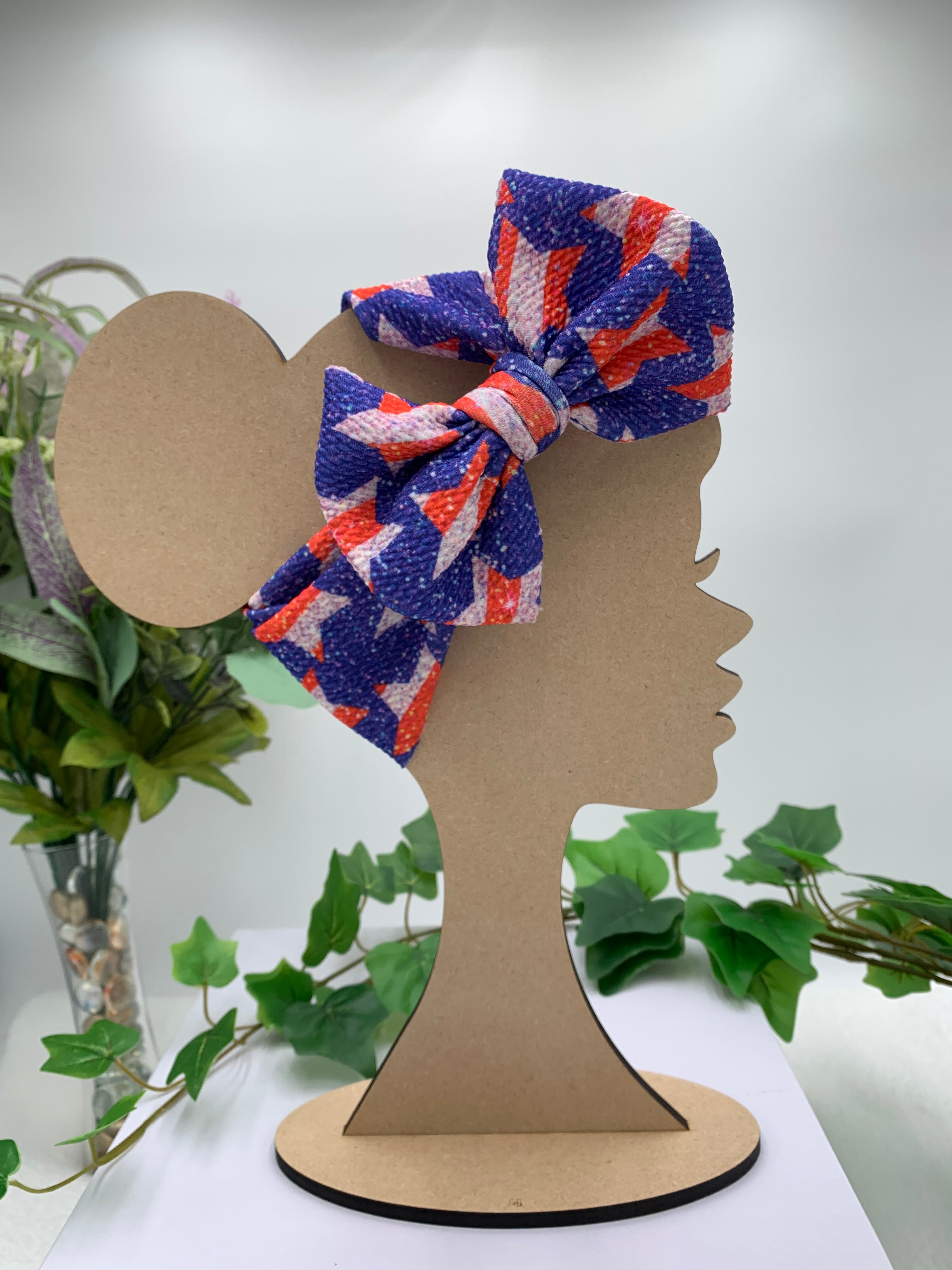 4th of July Star themed big bow headband on a mannequin head with a white background and greenery 