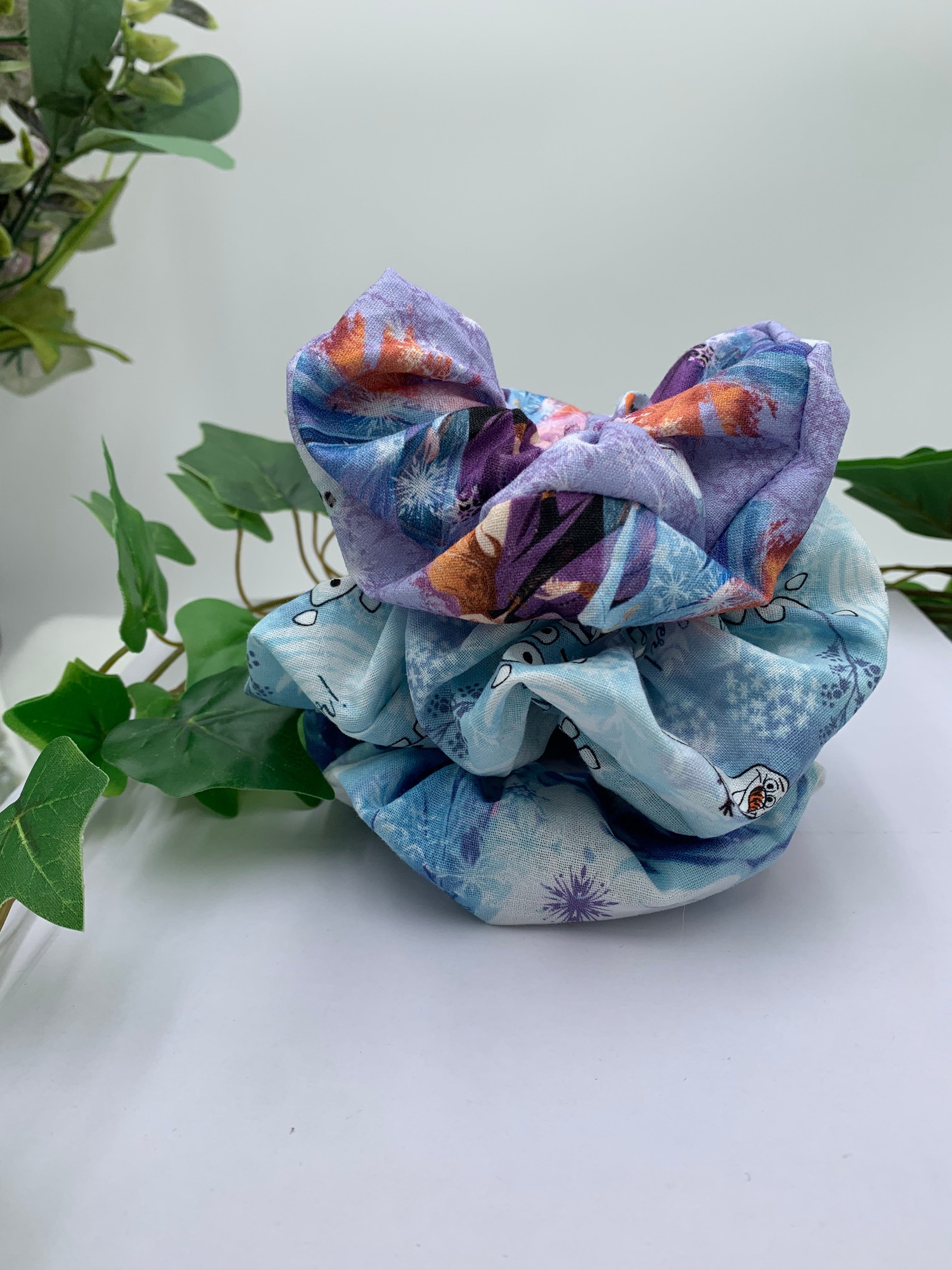 Three Colorful scrunchie with cartoon character on a white background with greenery 