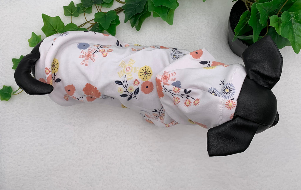birdseye view of Black dog mannequin with floral pattern hoodie on a white background with a potted green plant