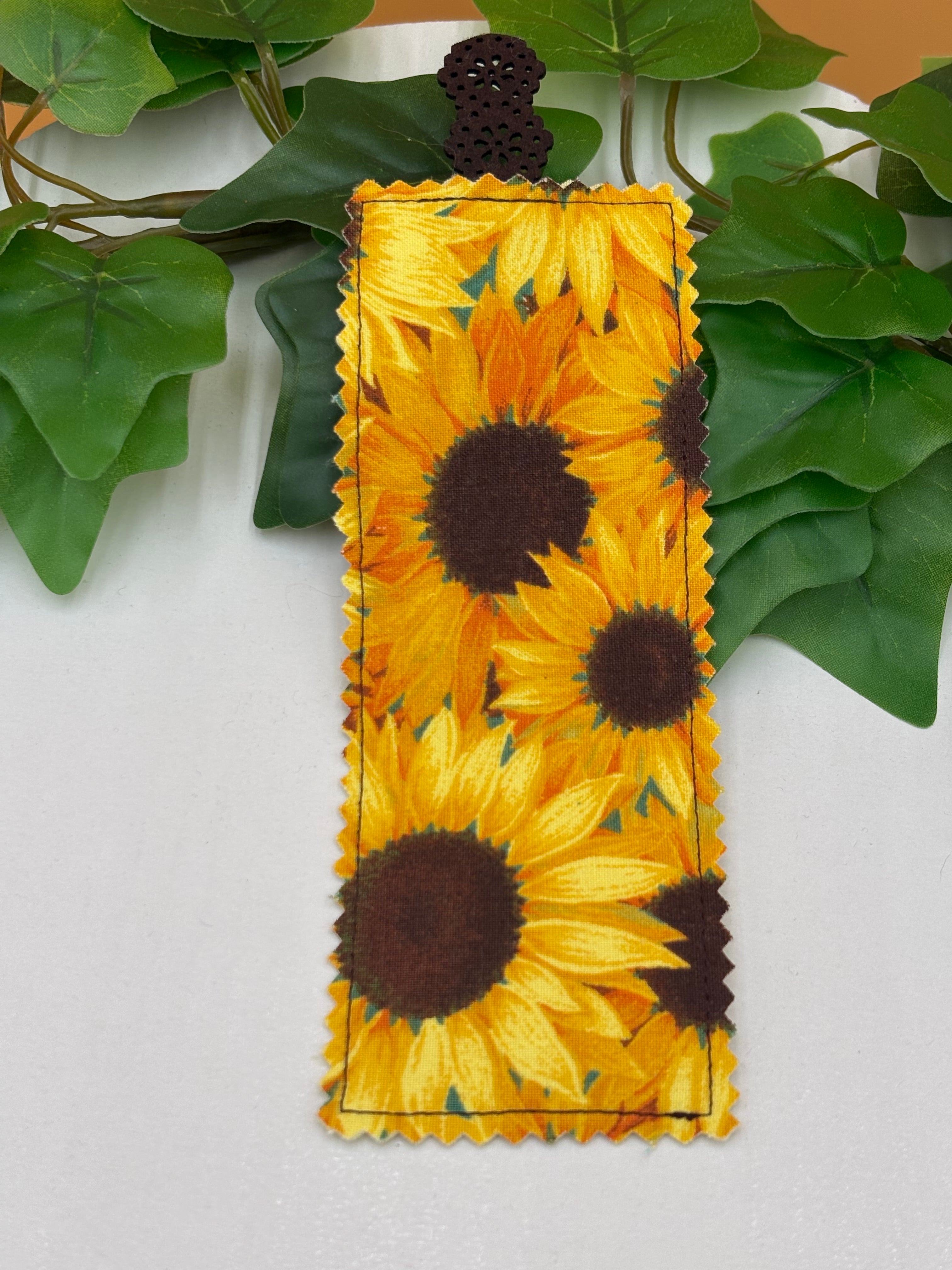 Sunflower-patterned fabric bookmark on a white background with green leaves.