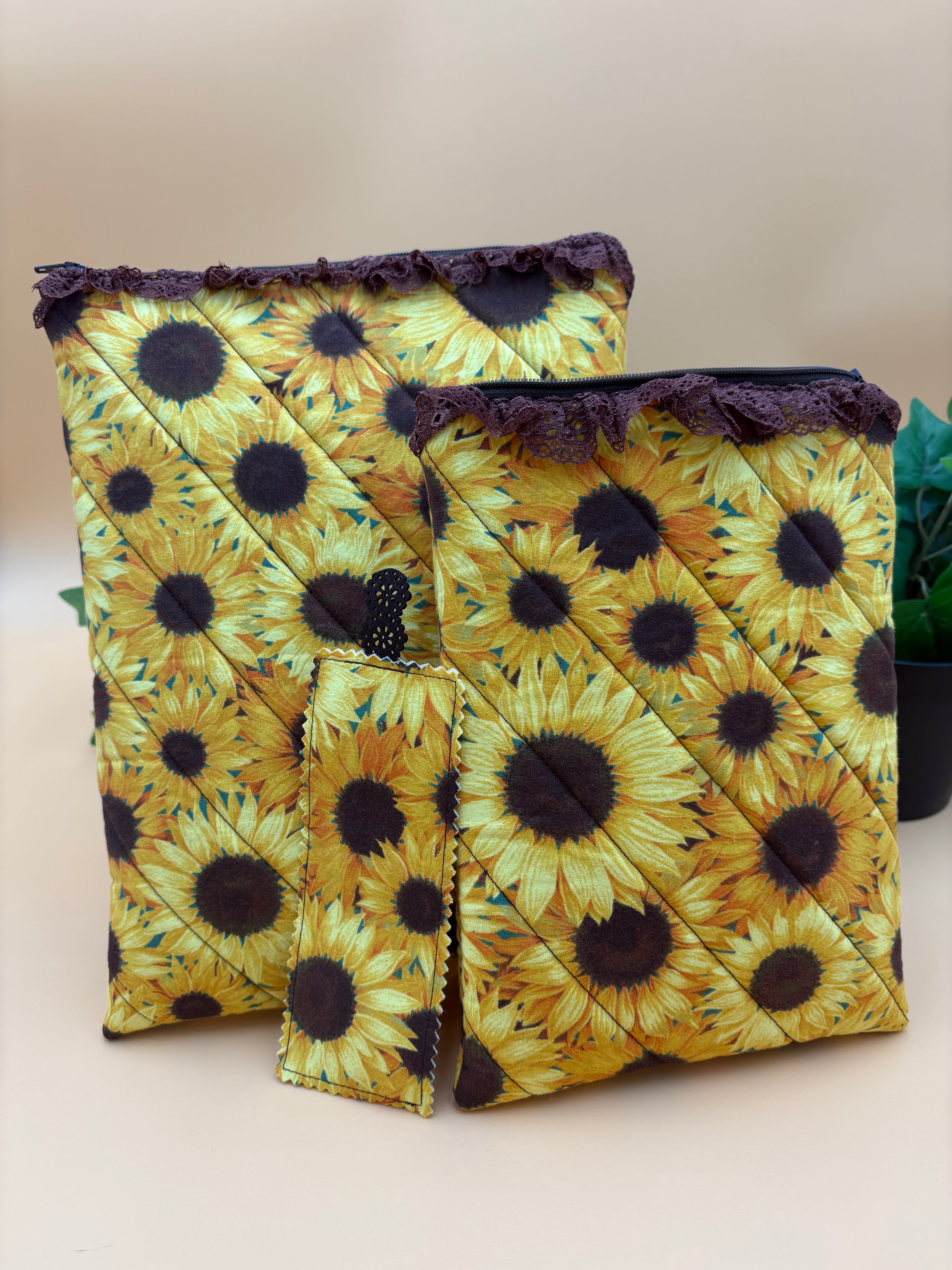 Quilted sunflower pattern with brown lace tablet and kindle/book sleeve with a fabric sunflower bookmark on a tan background with a potted green plant