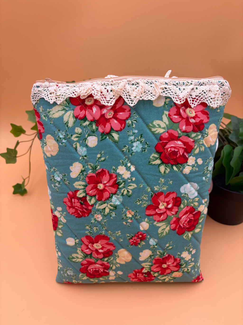 Quilted Teal Floral pattern with beige lace tablet sleeve on a tan background with a potted green plant