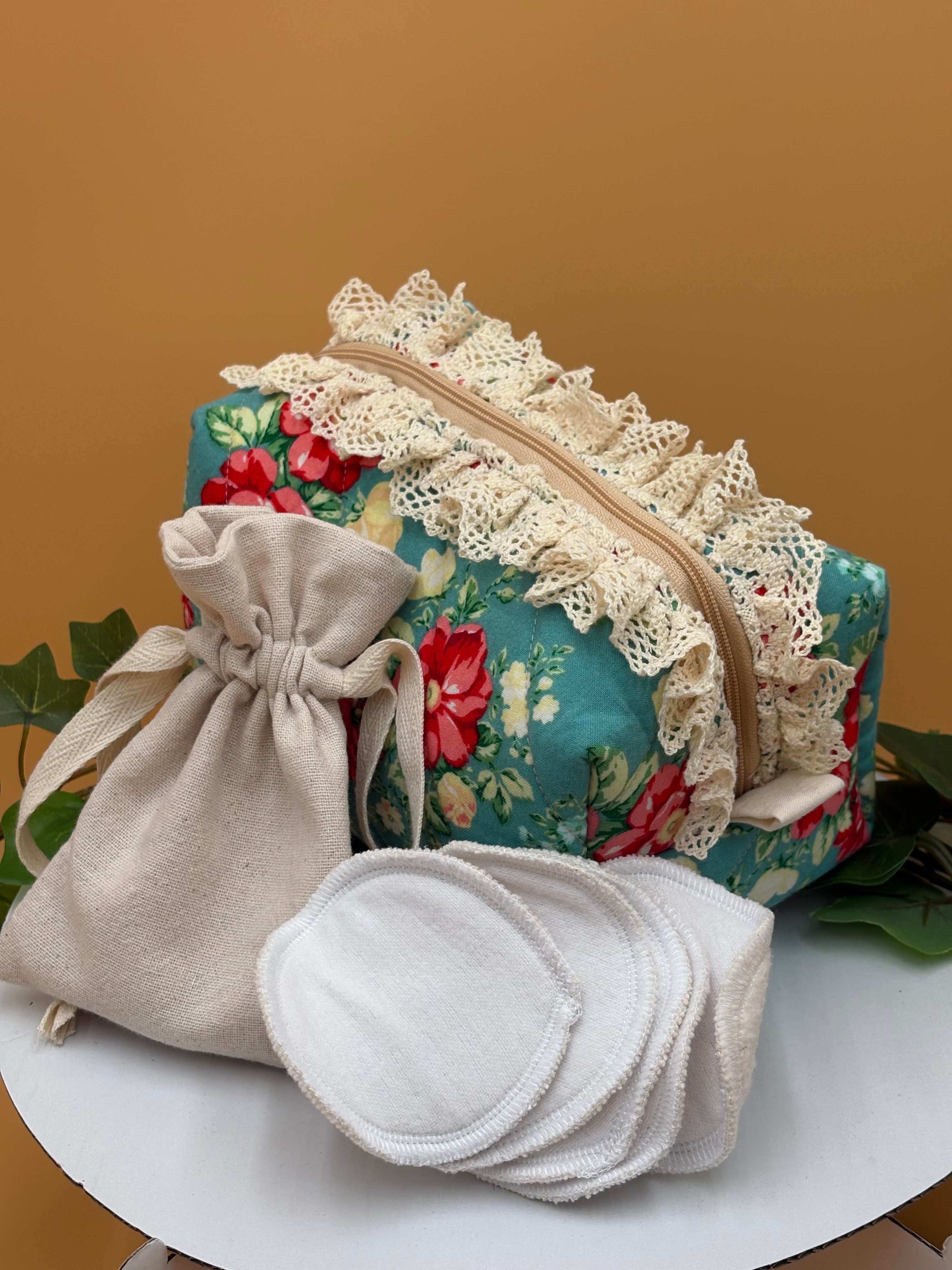 Teal Floral fabric boxy makeup bag with a beige drawstring bag, and 5 facial rounds on a tan background with green leaves