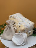Pale Peach Floral fabric boxy makeup bag with a white lace, beige drawstring bag and 5 facial rounds on a tan background with green leaves