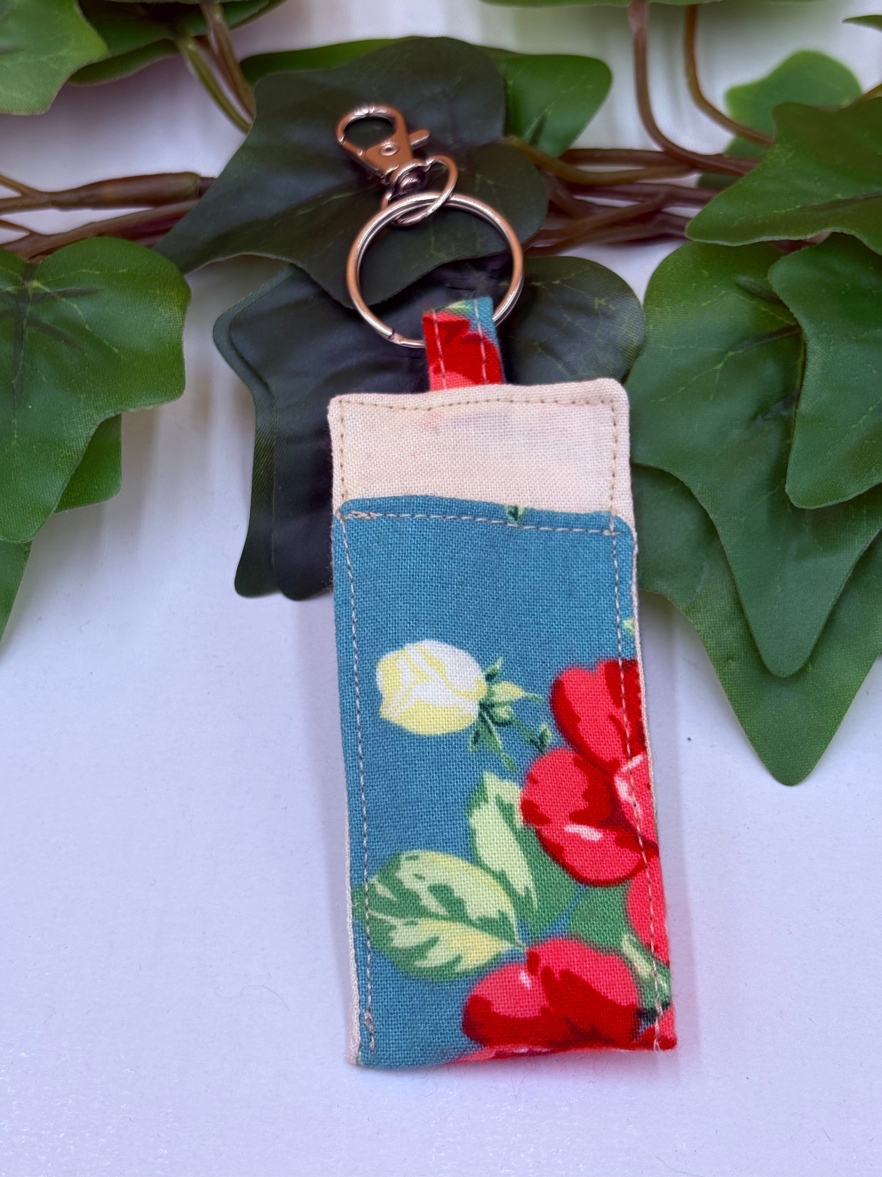 Teal floral pattern coin purse keychain on a white background with green leaves