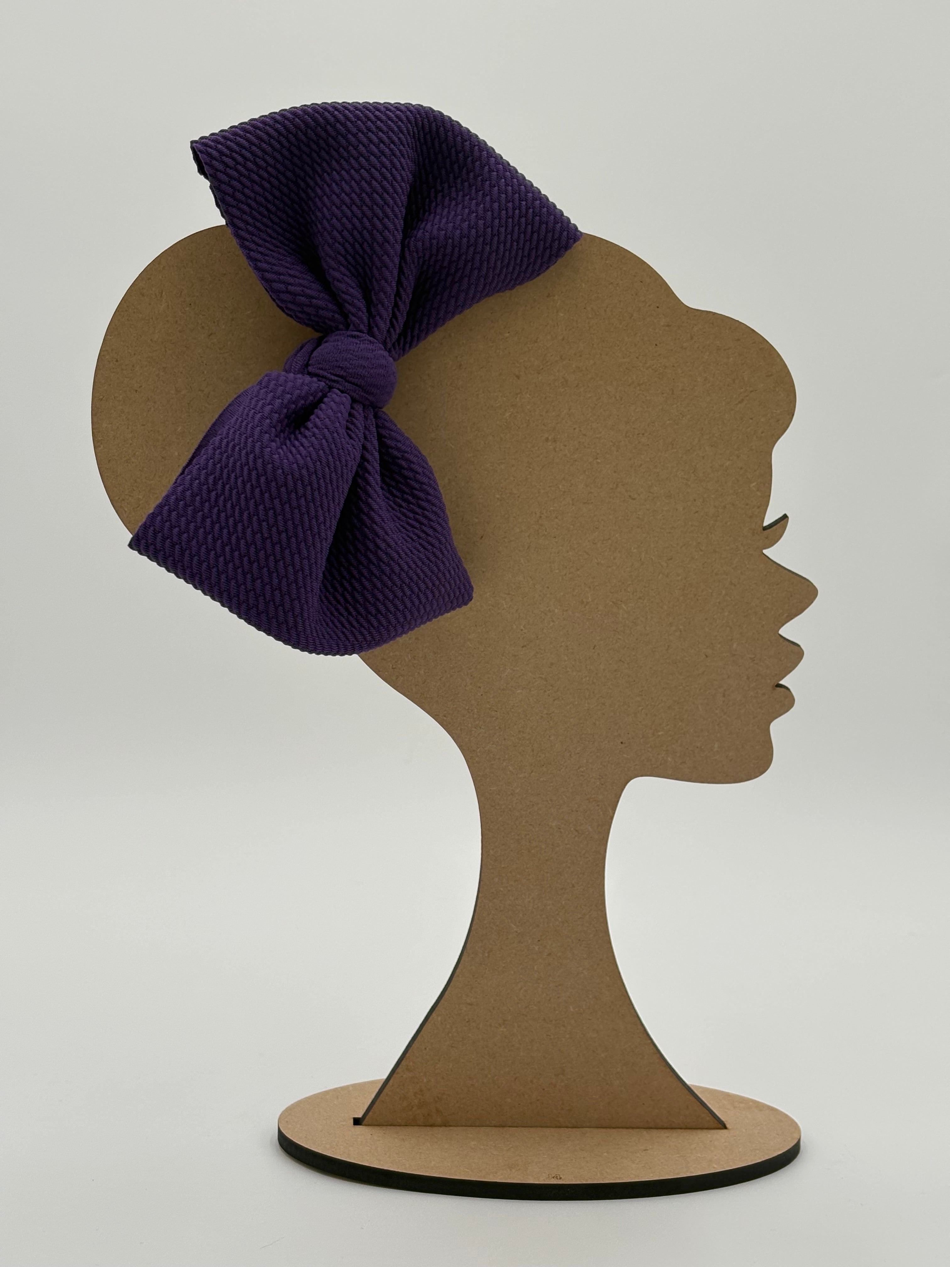 Brown cardboard cutout of a woman's silhouette with a purple bow on a white background