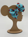 Wooden mannequin head cutout with an 4th of July themed patterned big bow nylon headband against a white background