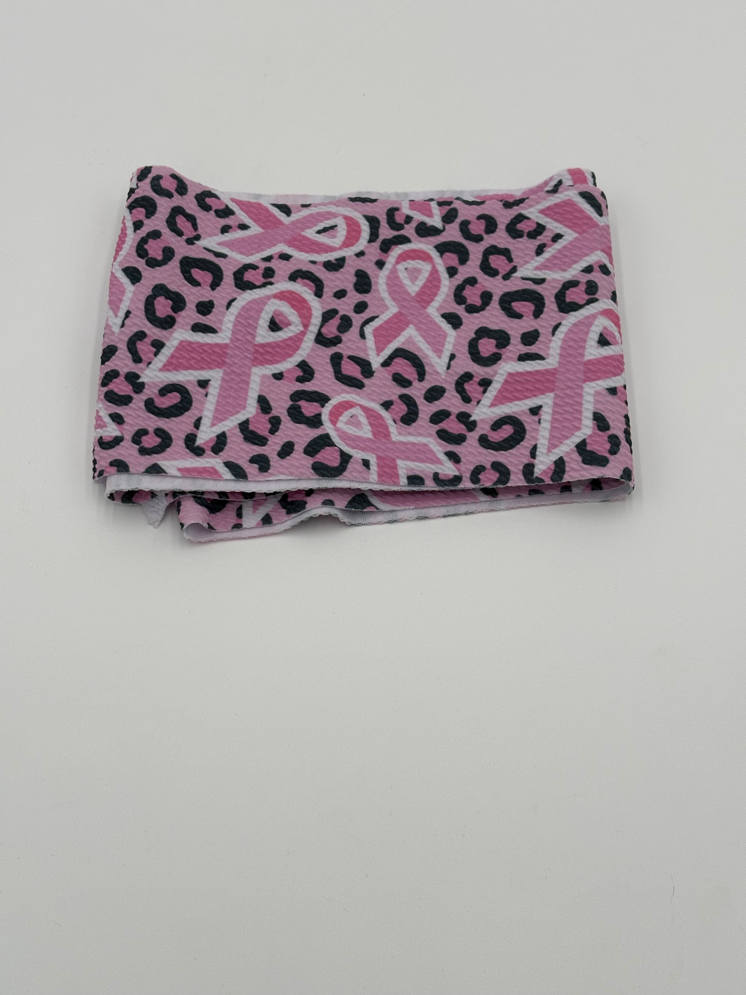 Folded fabric with pink breast cancer awareness ribbons on a leopard print background