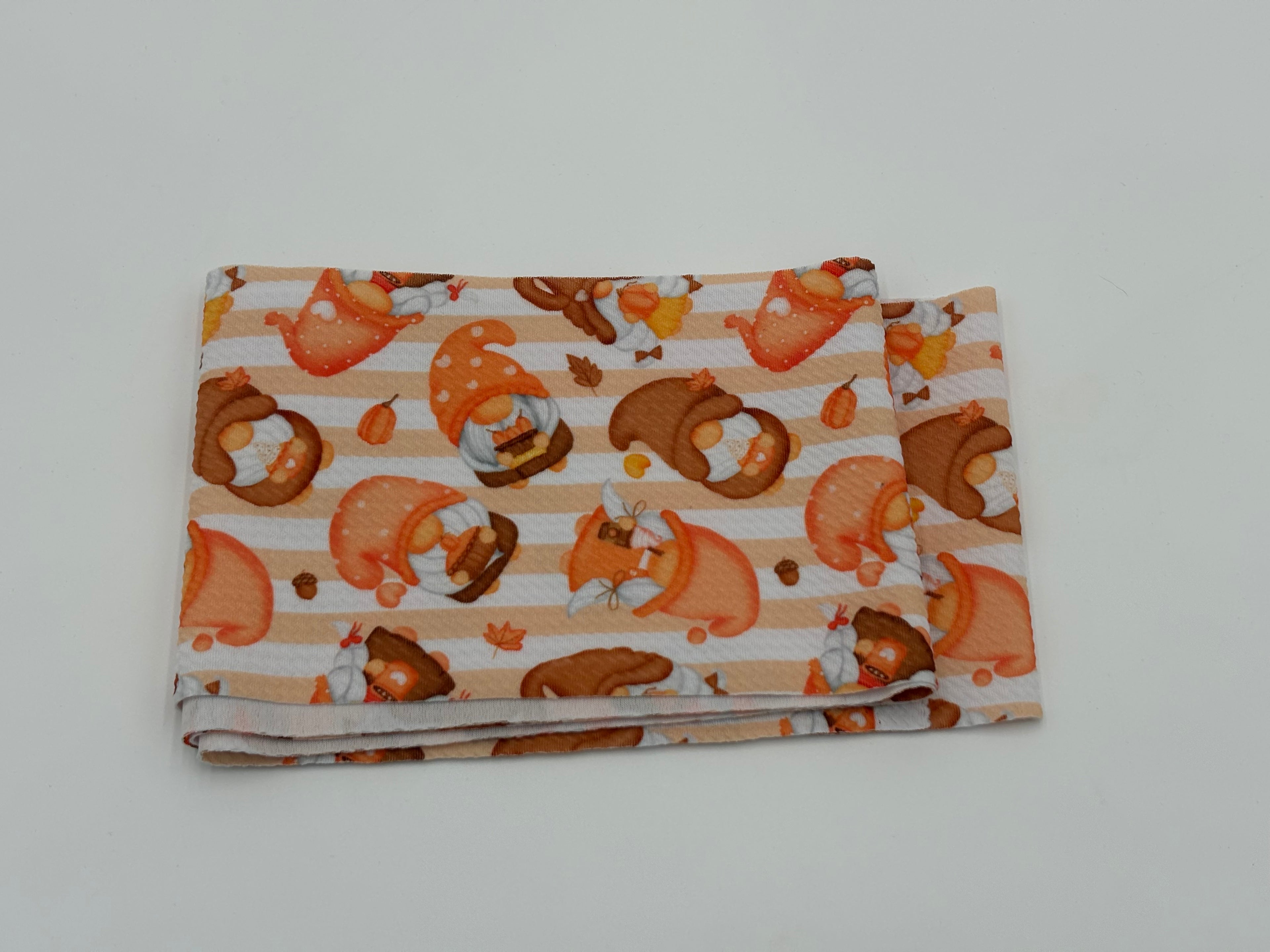 Folded fabric with Autumn gnomes pattern on a white background