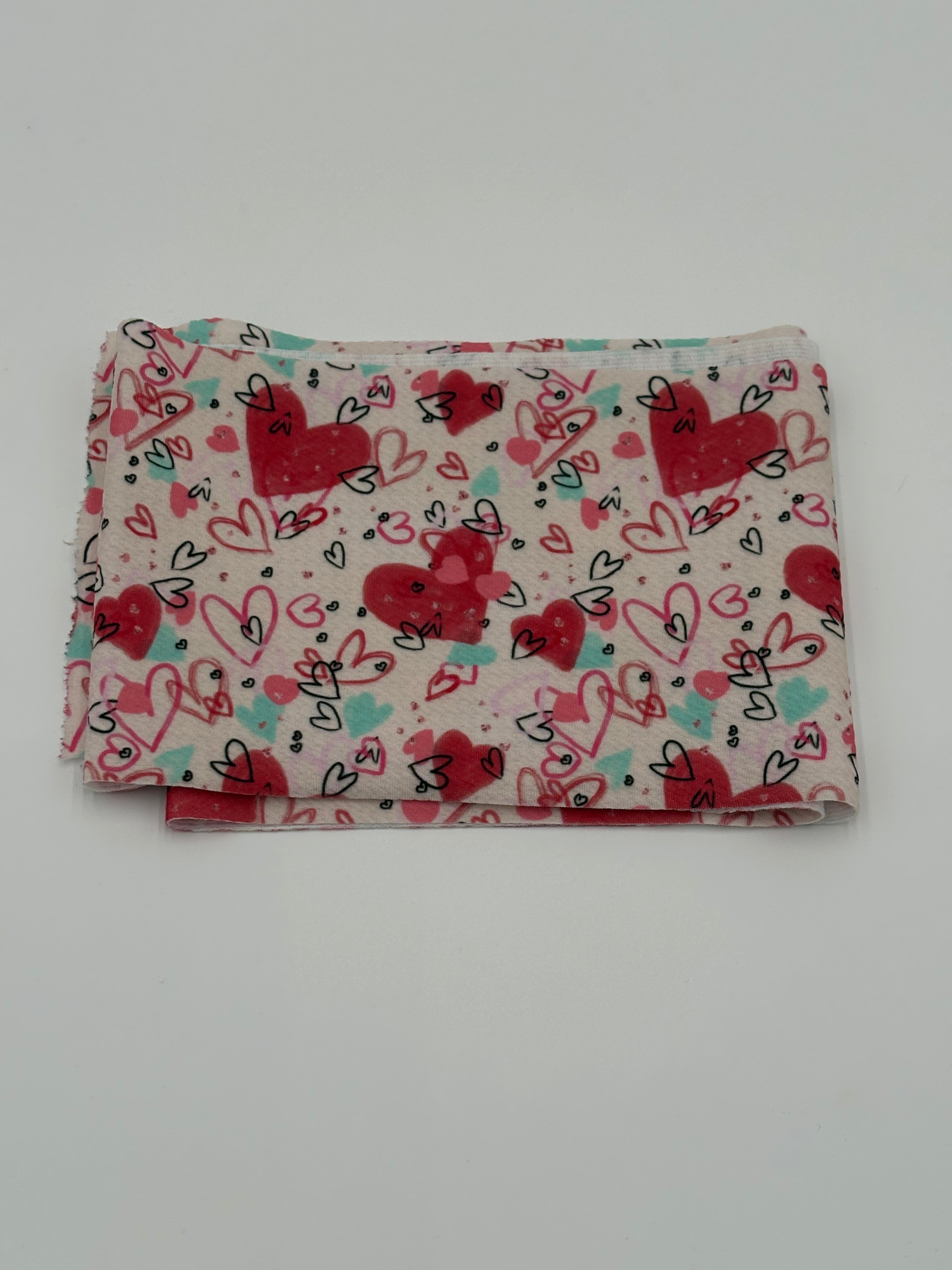 Folded fabric with Valentine’s Day hearts theme pattern on a white background