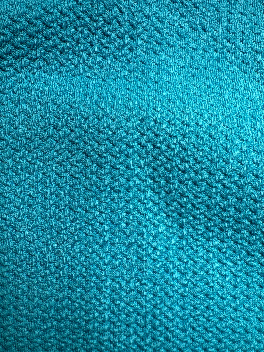 Close-up of aqua blue fabric with a textured pattern