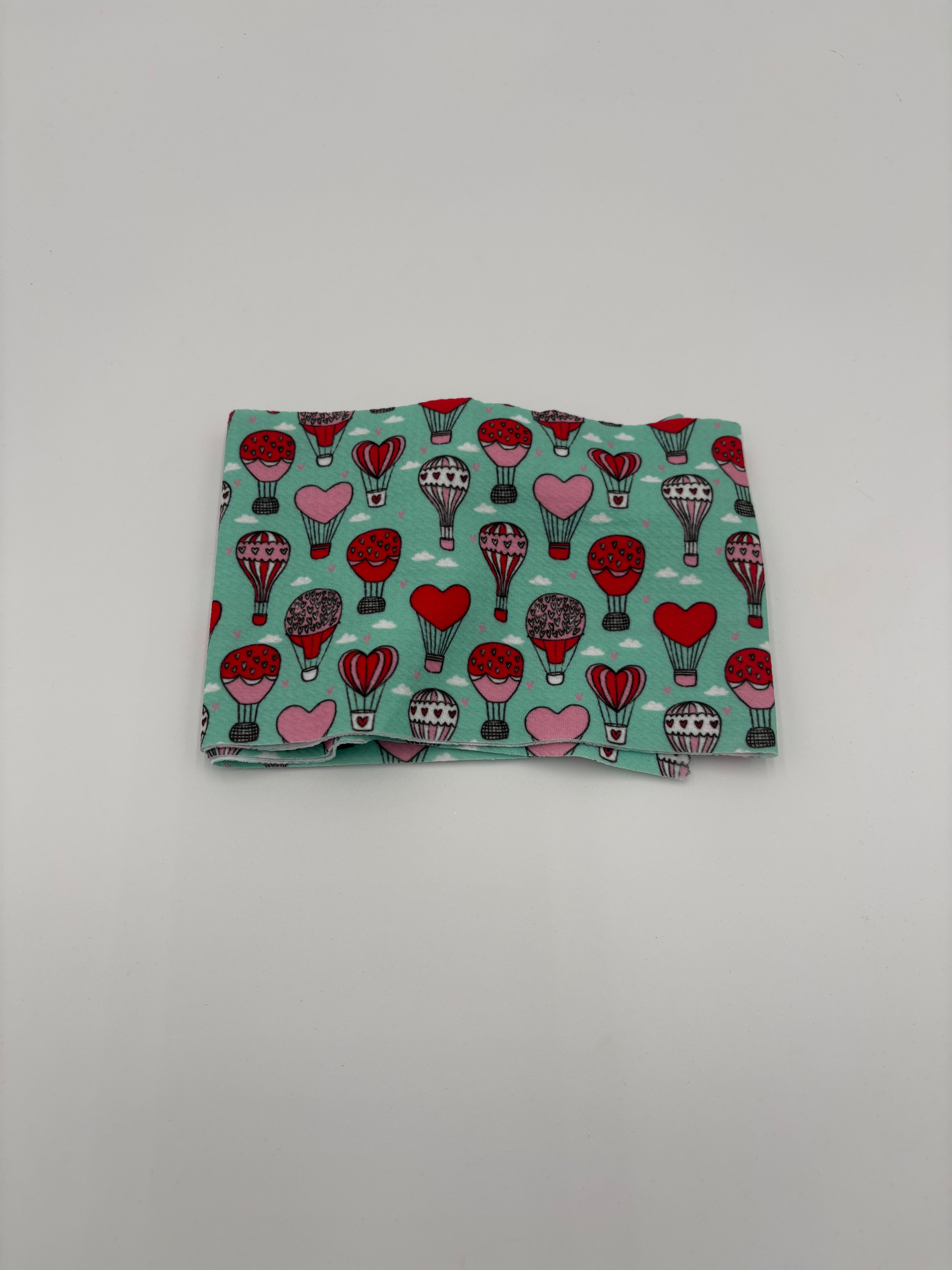 Folded fabric with Valentine’s Day heart hot air balloons pattern on a white background