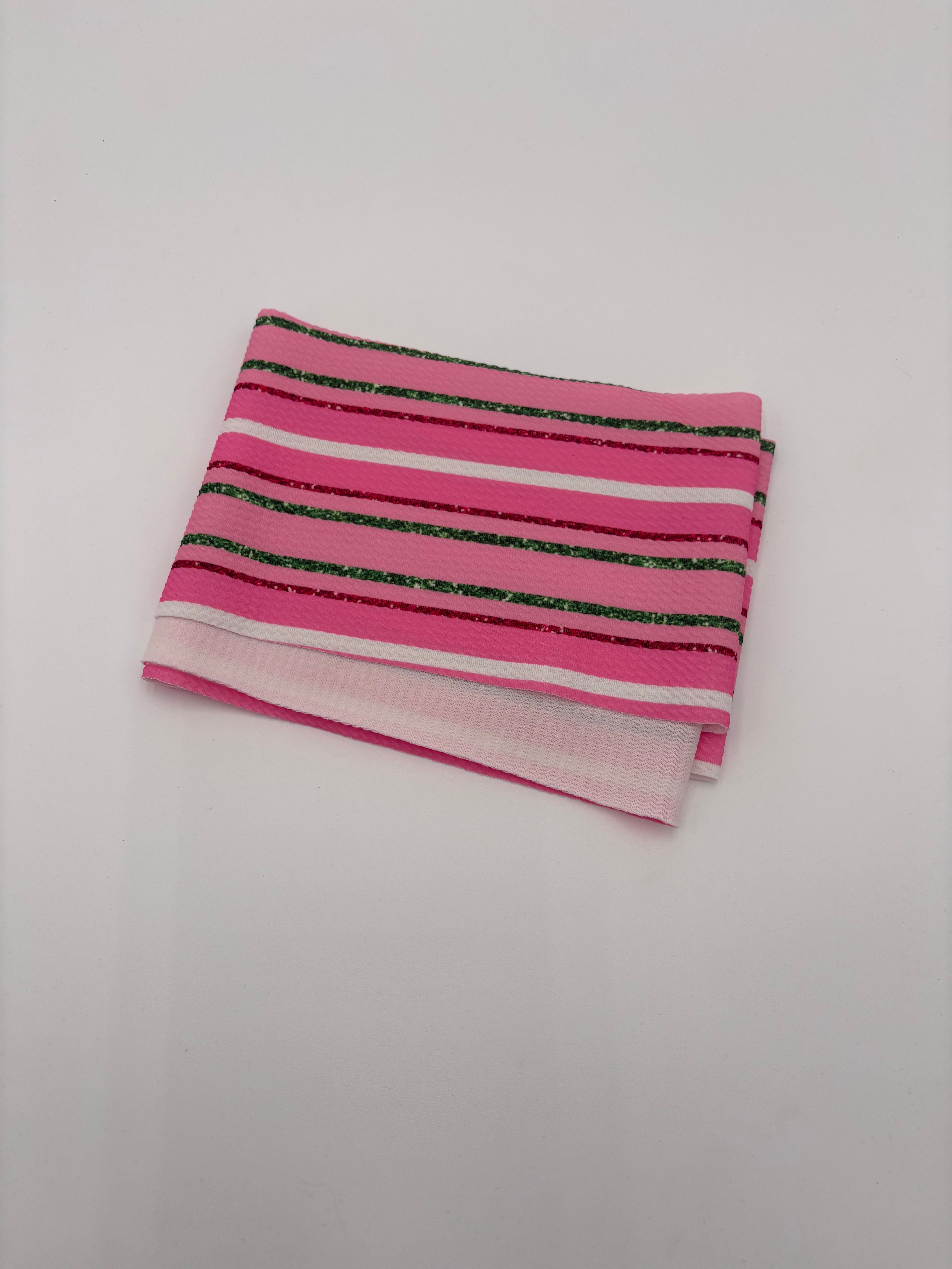 Pink fabric with green and white striped pattern on a white background