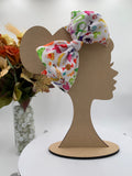 Colorful halloween candy themed big bow headband on a mannequin head with a white background and greenery 