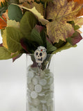 Bouquet of flowers with a skeleton nurse head badge holder in a clear vase on a white background