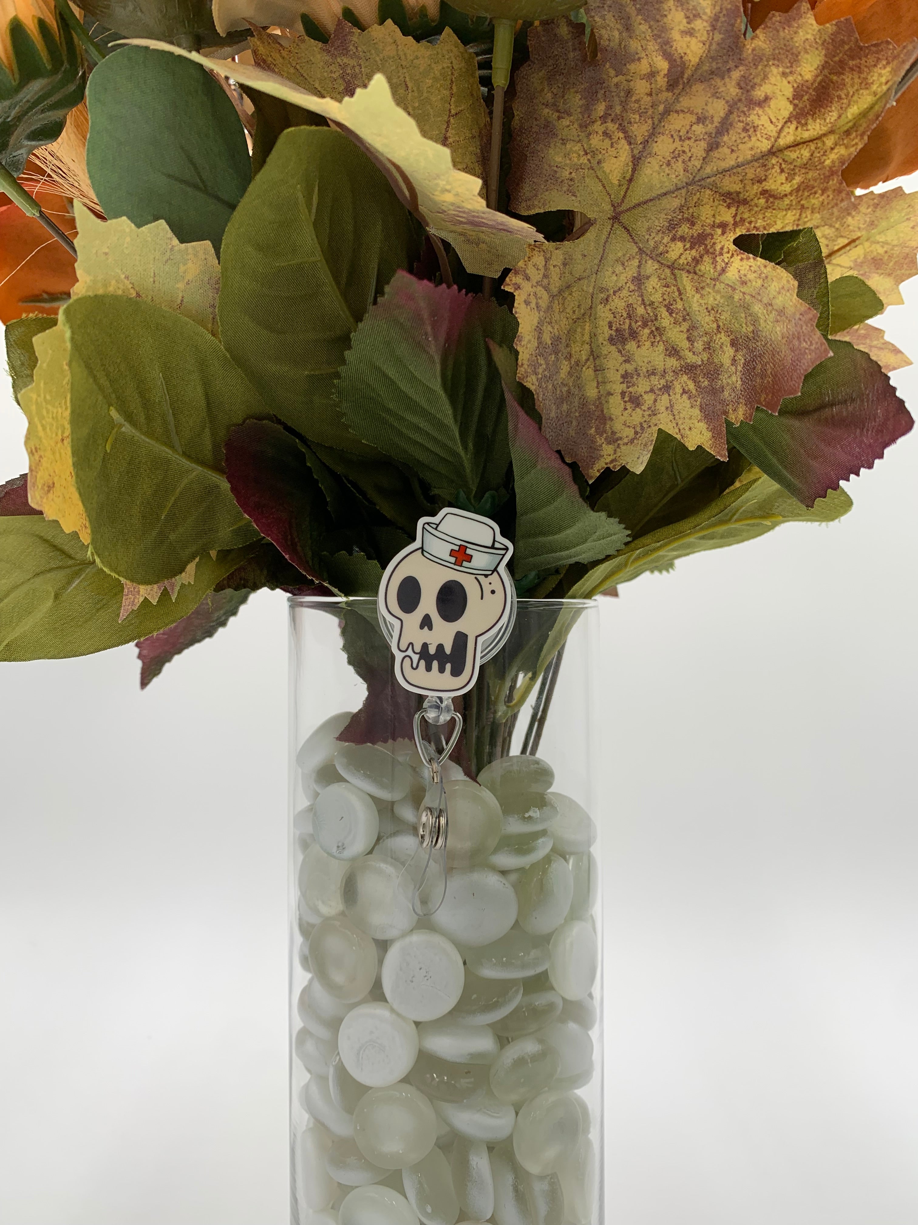 Bouquet of flowers with a skeleton nurse head badge holder in a clear vase on a white background