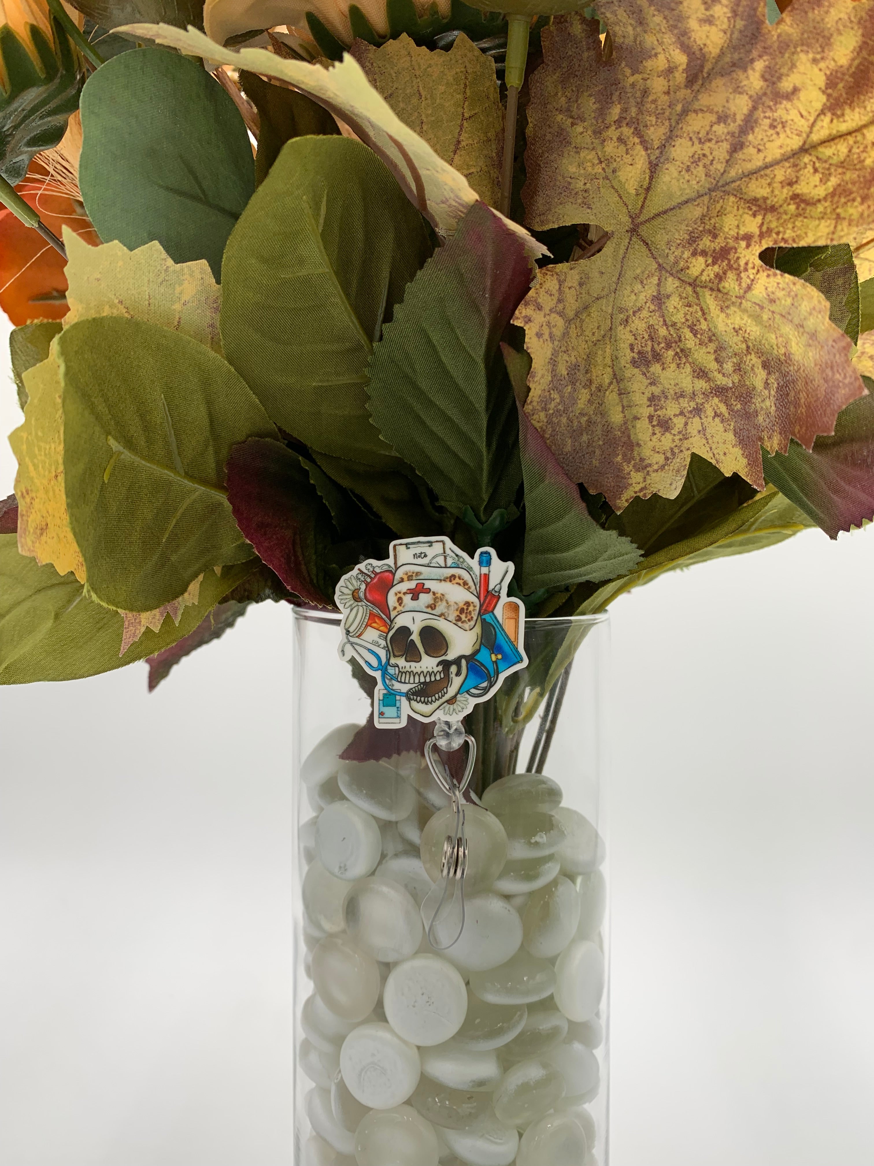 Bouquet of flowers with a skeleton nurse head badge holder in a clear vase on a white background