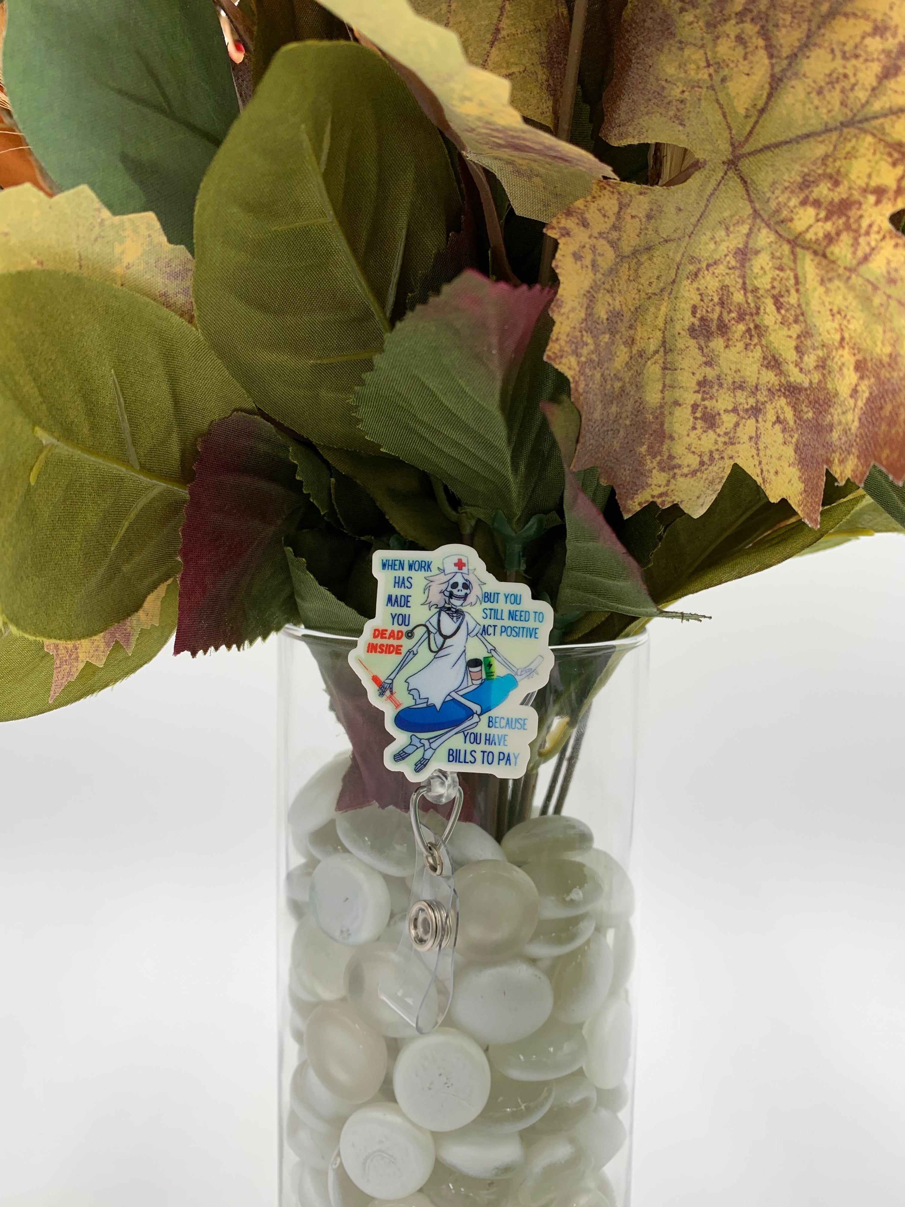 Bouquet of flowers with a Skeleton Nurse on Surf Board badge holder in a clear vase on a white background