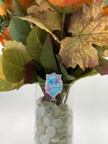 Bouquet of flowers with a man with a mask with text "Ravenclaw" badge holder in a clear vase on a white background