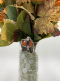 Bouquet of flowers with a man with a white mask holding a machete badge holder in a clear vase on a white background
