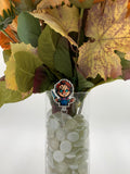 Bouquet of flowers with a killer doll holding a knife badge holder in a clear vase on a white background