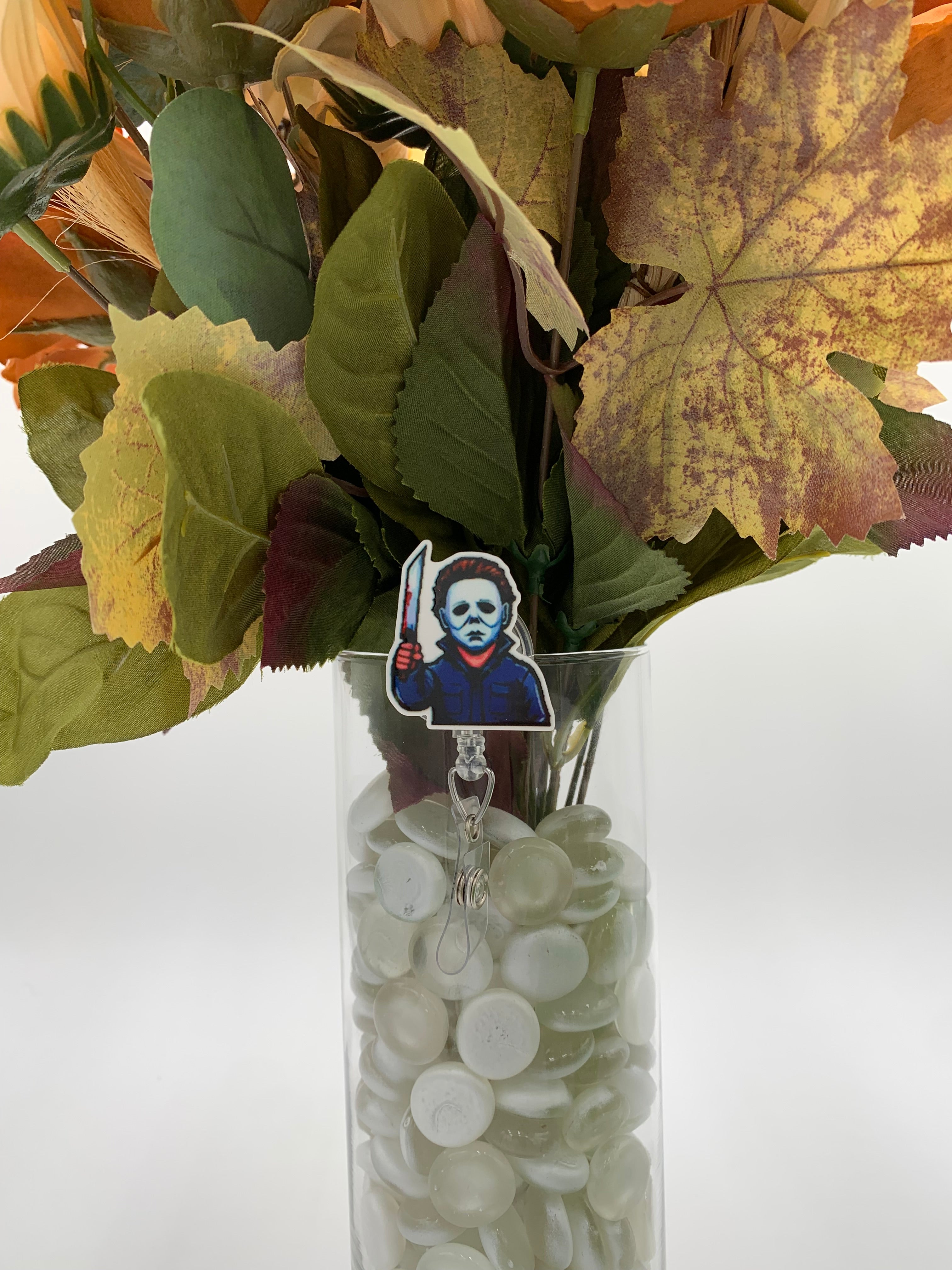 Bouquet of flowers with a man with a white mask holding a butcher knife badge holder in a clear vase on a white background