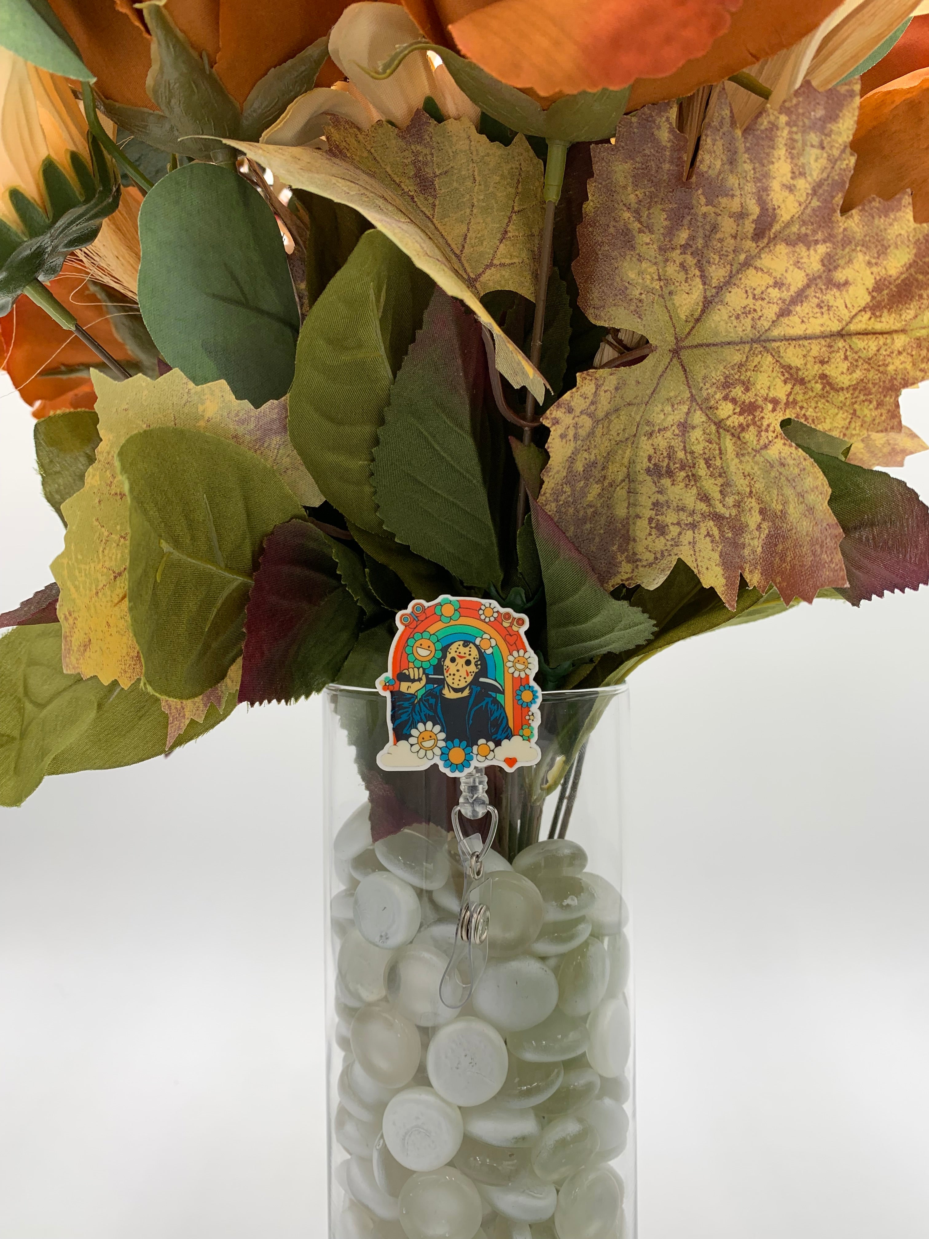 Bouquet of flowers with a man with a white mask holding a machete with a rainbow covered in flowers badge holder in a clear vase on a white background