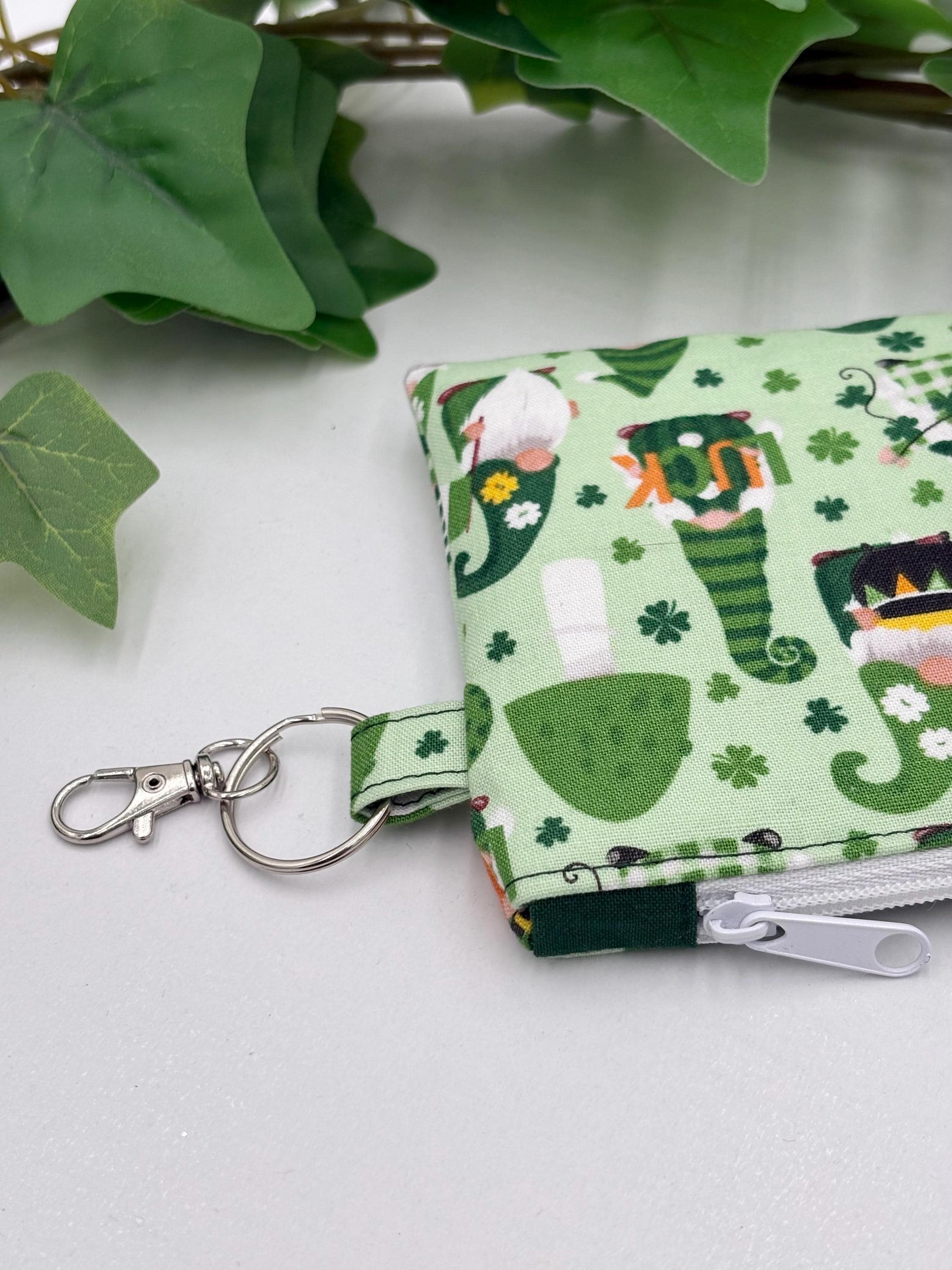 close up of keychain on Small coin purse keychain with green st. patrick's day gnomes pattern on a white background with green leaves
