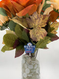 Bouquet of artificial flowers with a 'Nurse of Progress' badge reel in a clear vase on a white background