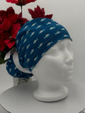 Blue Scrub cap with shark pattern on a mannequin head against a white background with red flowers