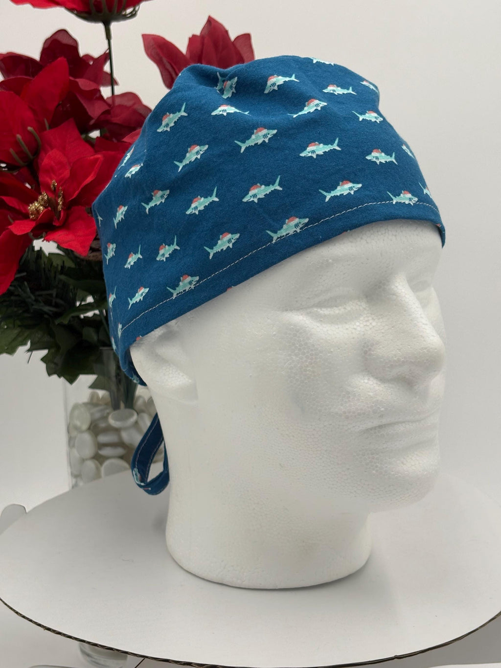 Blue scrub cap with shark pattern on a mannequin head against a white background