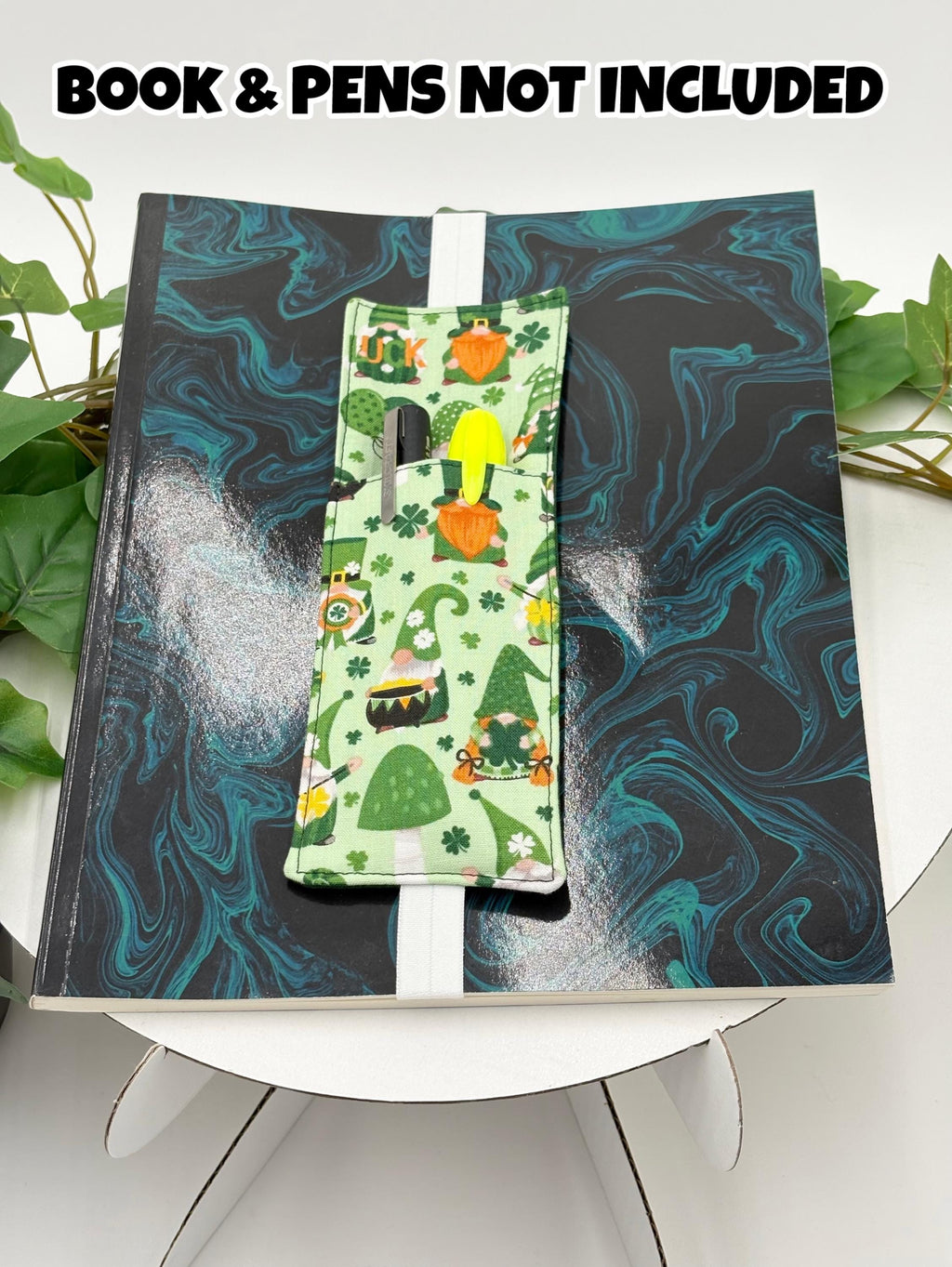 Green pen holder book mark with gnomes pattern on a marbled black and blue surface, with text 'Book & Pens Not Included'.