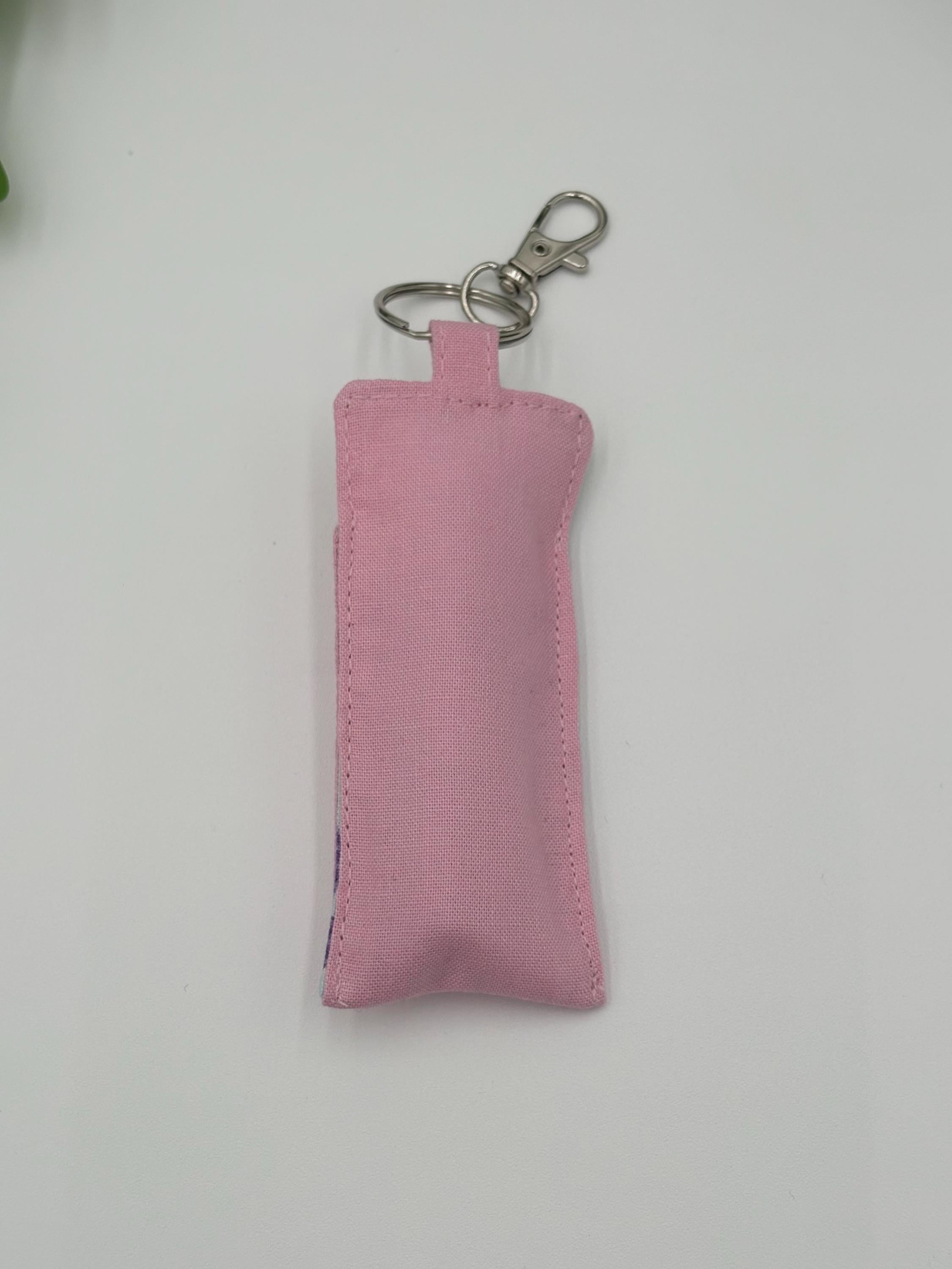 back of Pink easter themed chapstick holder on a white surface with green leaves in the background 