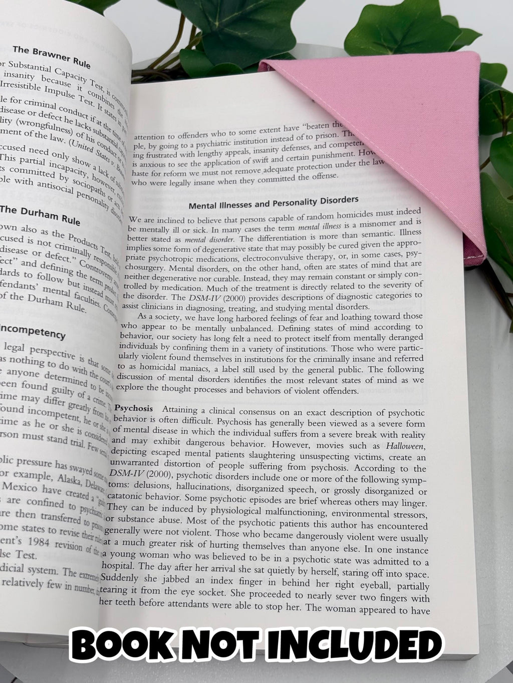 Open book with text, with pink corner bookmark attached and  green leaves in the background