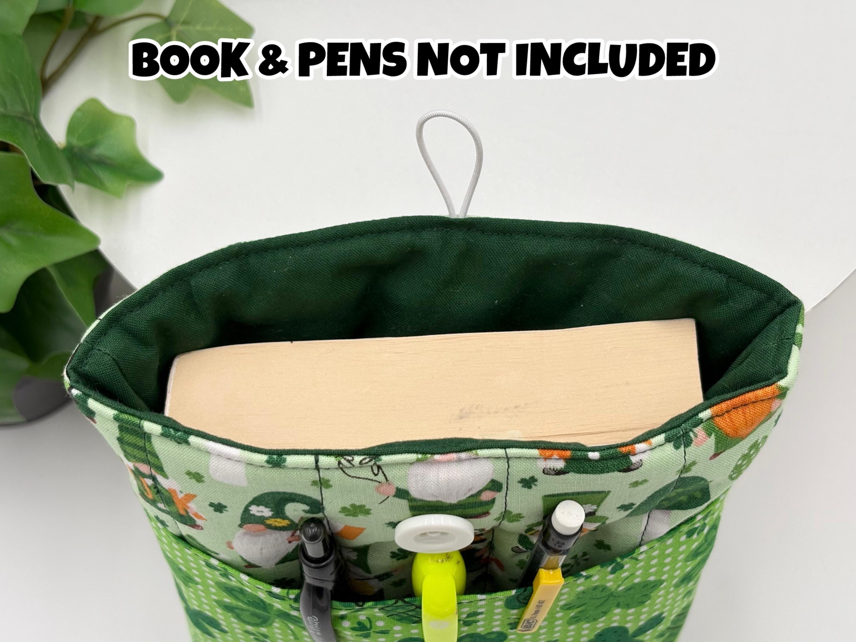 Green saint Patrick’s day gnomes and shamrocks patterned book sleeve with pens and book inside it on a white surface and text “book and pens not included”