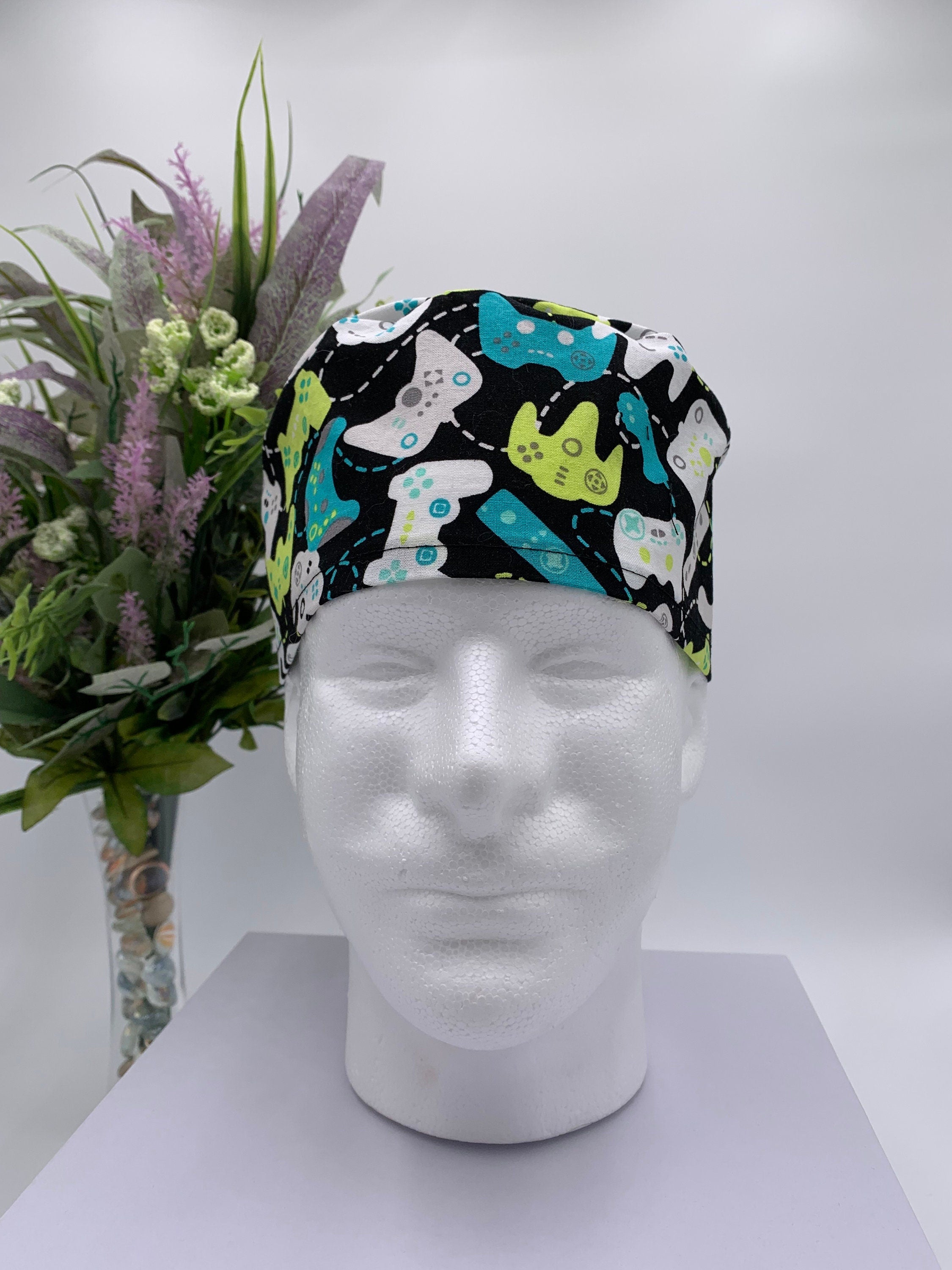 Colorful game controller scrub cap on a mannequin head with a bouquet of flowers in the background
