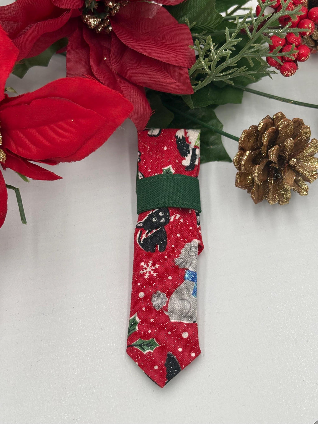 Red over the collar necktie with Christmas-themed dogs design on a white background with poinsettias and a pine cone.