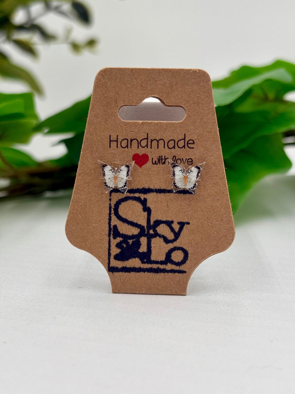 White and black Butterfly earrings on a 'Handmade with Love' branded card with a green leafy background.